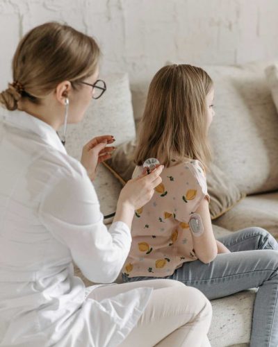 Doctor conducting a health check on a young girl managing diabetes at home.